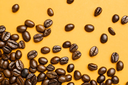 Scattered coffee beans on orange backgroundの写真素材