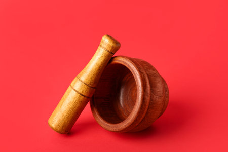Wooden mortar and pestle on red backgroundの写真素材