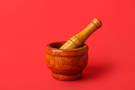Wooden mortar and pestle on red backgroundの写真素材