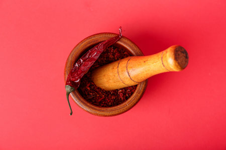Wooden mortar and pestle with spices on red backgroundの写真素材