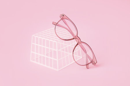 Stylish eyeglasses and plastic box on pale pink backgroundの写真素材