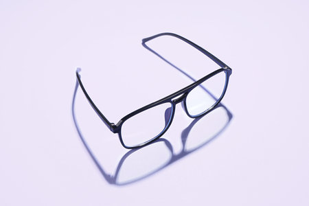 Modern black eyeglasses on pale purple backgroundの写真素材