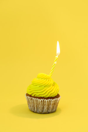 Tasty cupcake with birthday candle on yellow backgroundの写真素材
