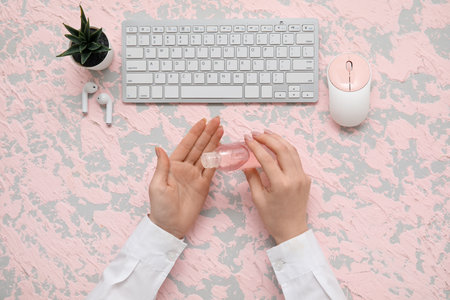 Woman applying hand sanitizer at table in officeの写真素材