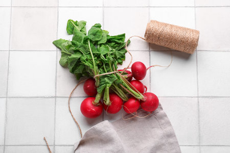 Fresh radishes with leaves on light tile backgroundの写真素材