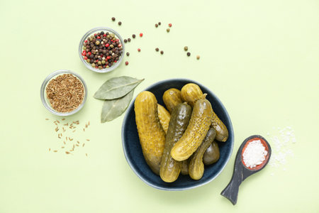Bowl of tasty canned cucumbers with spices on pale green backgroundの写真素材