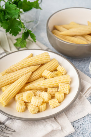 Plate with tasty canned corn cobs on light backgroundの写真素材