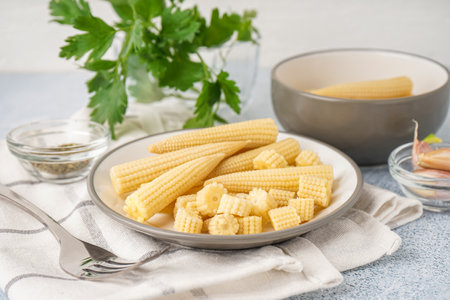 Plate with tasty canned corn cobs on light backgroundの写真素材