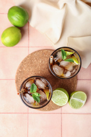 Glasses of cold Cuba Libre cocktail on light tile background