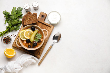 Pot of tasty Hodgepodge soup with bread and sour cream on light backgroundの写真素材
