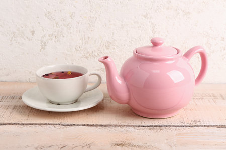 Ceramic teapot with cup of fruit tea on white wooden tableの写真素材