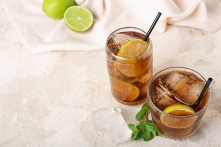 Glasses of tasty Cuba Libre cocktail on light background