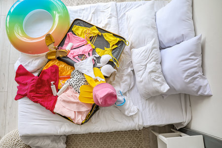 Open suitcase with beach accessories on bed in roomの写真素材