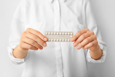 Woman with hormonal pills on white background, closeupの写真素材