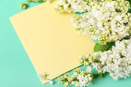 Yellow blank card and lilac flowers on turquoise backgroundの写真素材