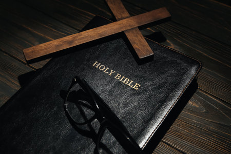 Holy Bible, cross and eyeglasses on wooden background, closeupの写真素材