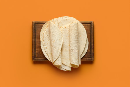 Board with thin lavash on orange backgroundの写真素材