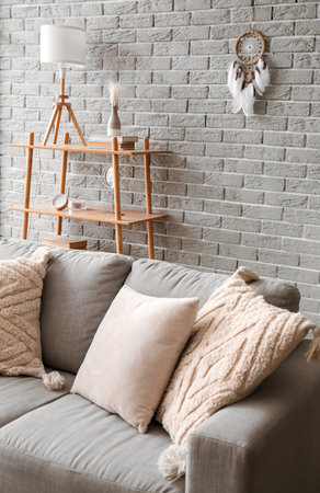 Interior of modern room with sofa, shelf unit and dream catcher on brick wallの写真素材