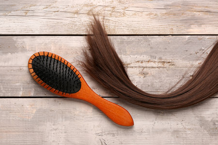 Brown hair strand with brush on wooden backgroundの写真素材
