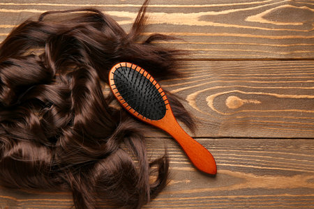 Curled brown hair with brush on wooden backgroundの写真素材