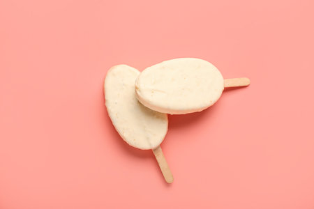 Delicious chocolate covered ice cream on stick against pink backgroundの写真素材