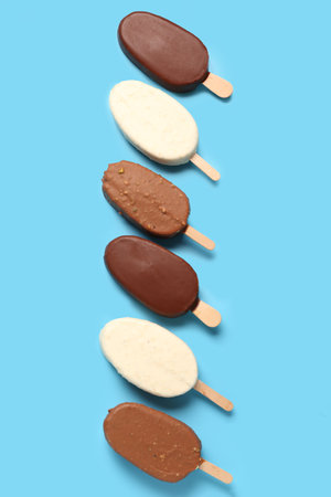 Composition with different chocolate covered ice cream on stick against blue backgroundの写真素材