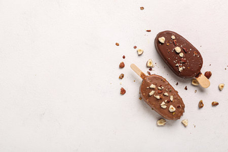 Delicious chocolate covered ice cream with crushed nuts on white tableの写真素材
