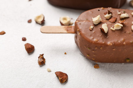 Delicious chocolate covered ice cream with crushed nuts on white table, closeupの写真素材