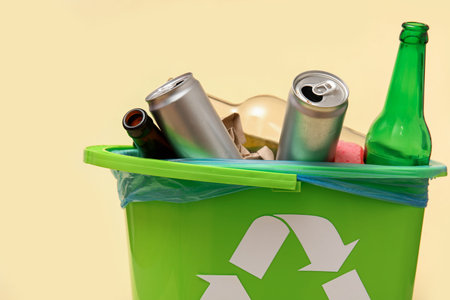 Trash bin with different garbage on beige background