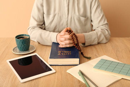 Woman with prayer beads and Holy Bible at table on beige background, closeupの写真素材