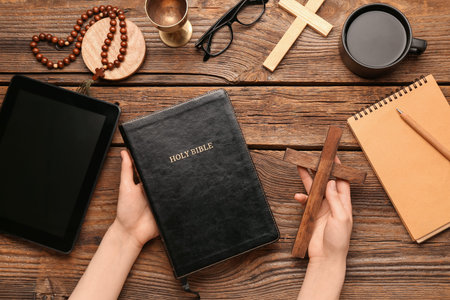 Woman with Holy Bible and cross on wooden background