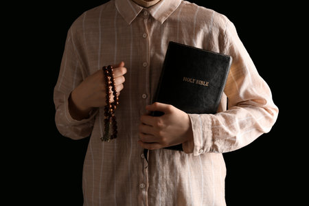 Woman with Holy Bible and prayer beads on black background, closeupの写真素材