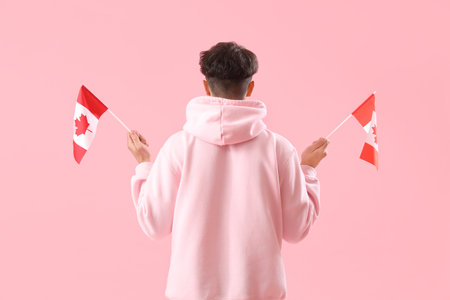 Young man with flags of Canada on pink background, back viewの写真素材