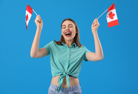 Young woman with flags of Canada on blue backgroundの写真素材