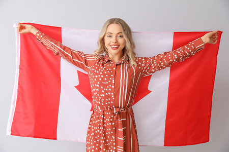 Young woman with flag of Canada on light backgroundの写真素材