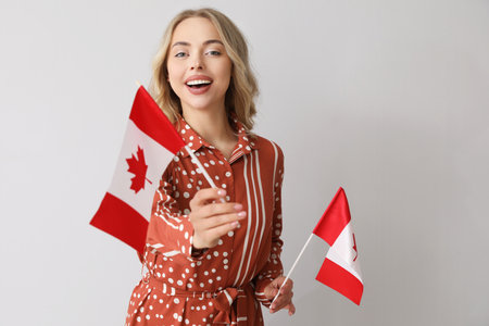 Young woman with flag of Canada on light backgroundの写真素材