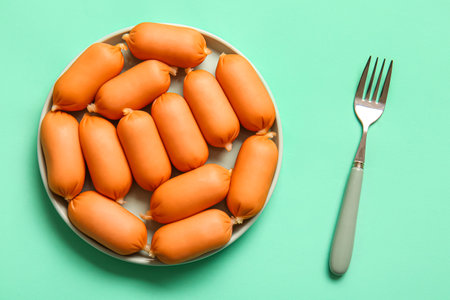 Plate of tasty boiled sausages on turquoise backgroundの写真素材