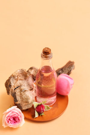 Bottle of cosmetic oil with rose extract and flowers on beige backgroundの写真素材
