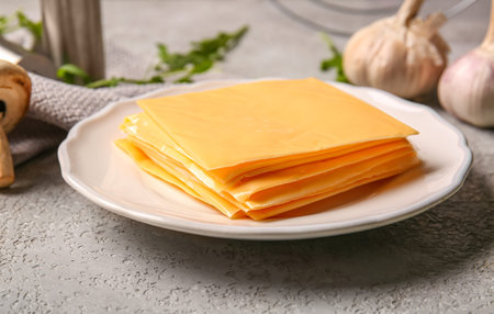Plate with slices of tasty processed cheese on grunge background