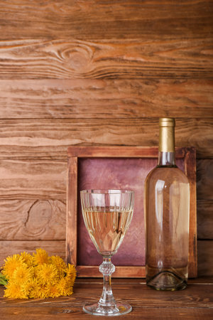 Bottle and glass of dandelion wine on wooden tableの写真素材