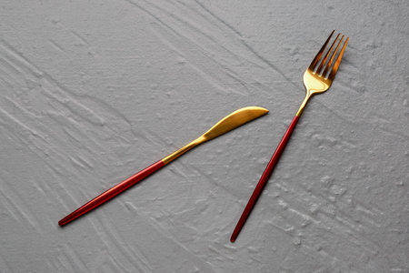 Stainless steel fork and knife on textured gray background
