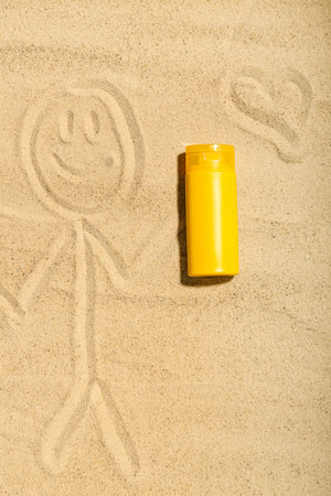 Creative composition with sunscreen cream and drawings on sand