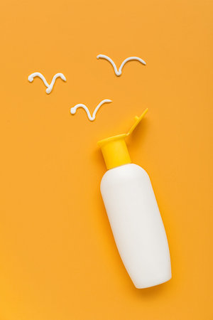Drawing of birds made with sunscreen cream on orange background