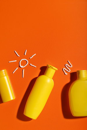 Drawings of sun made with sunscreen creams on orange backgroundの写真素材