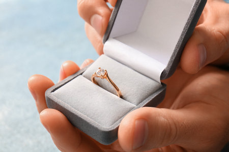 Man holding box with engagement ring on blue background, closeupの写真素材
