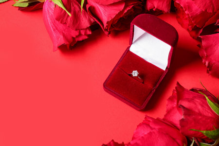 Box with engagement ring and roses on red backgroundの写真素材