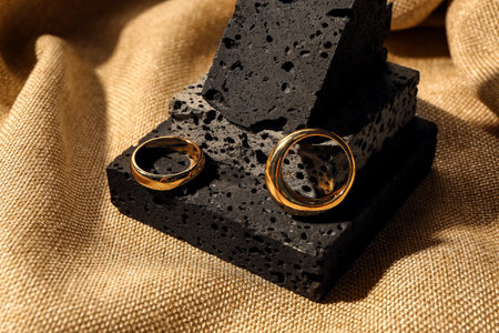 Decorative podium with beautiful rings on beige fabric background