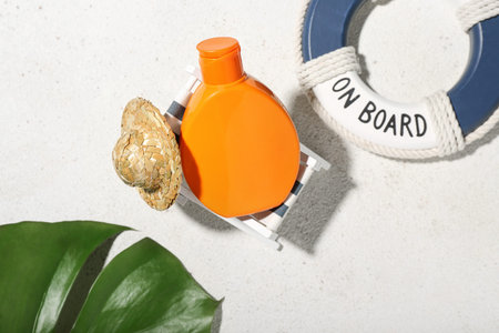 Creative composition with sunscreen cream and palm leaf on gray background