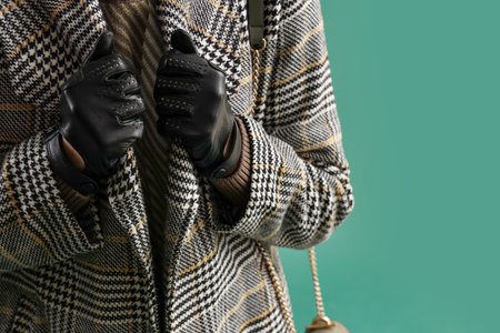 Beautiful woman in leather gloves and coat on green background, closeupの写真素材