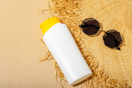 Creative composition with sunscreen cream, summer hat and sunglasses on beige background